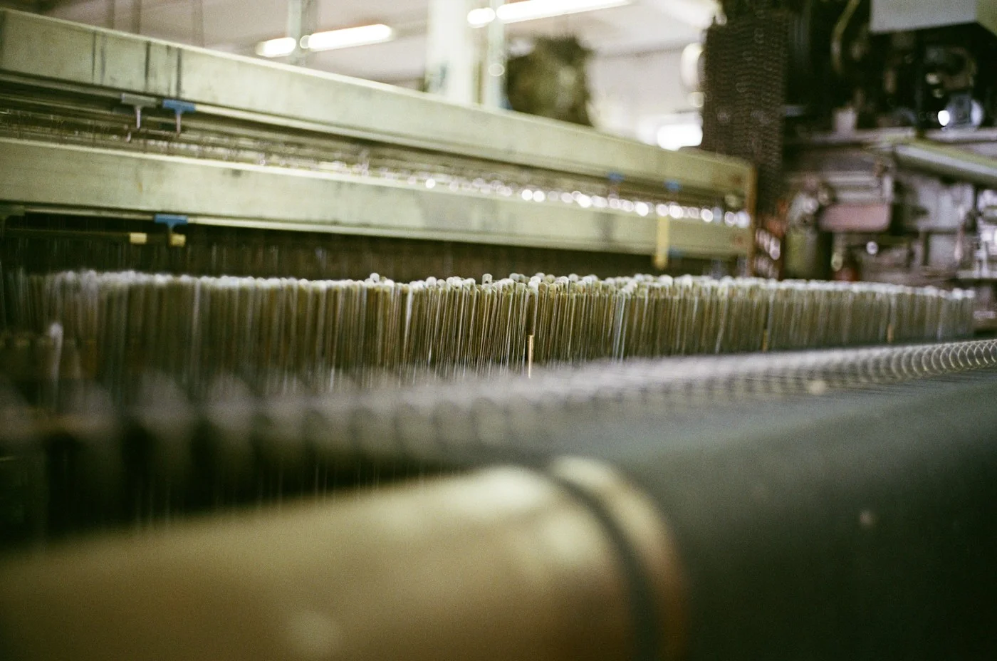 Close-up of threads running through an industrial weaving loom