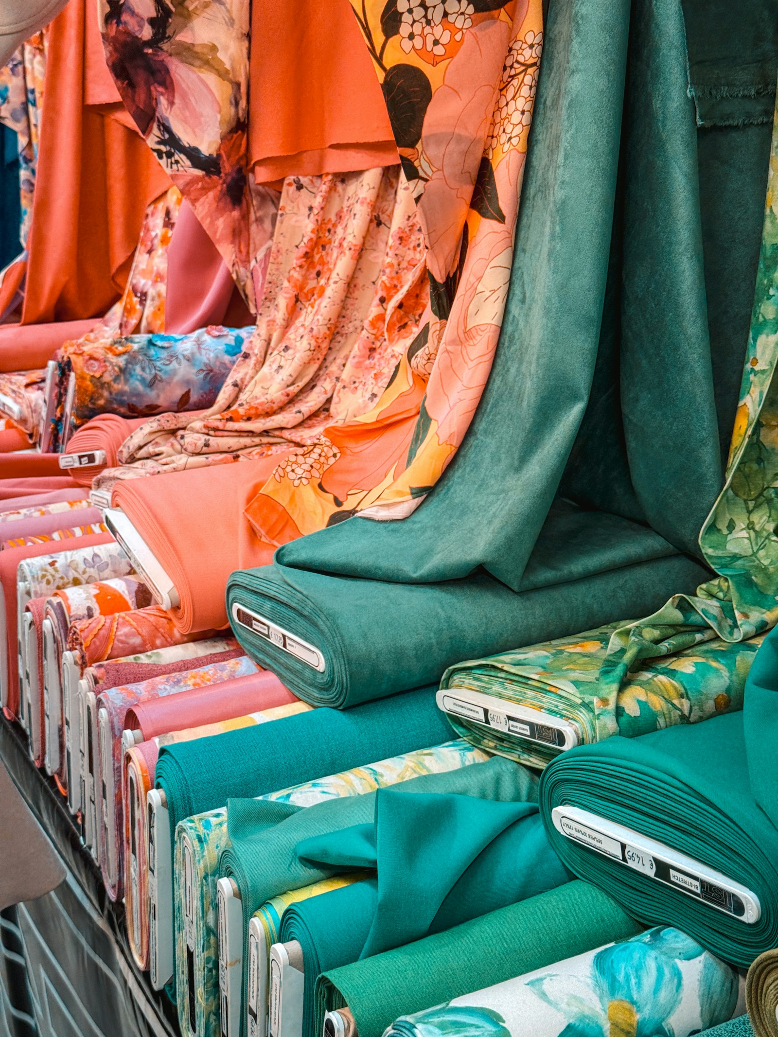 Teal and warm coral fabric rolls and draped textiles