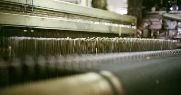 Close-up of threads running through an industrial weaving loom