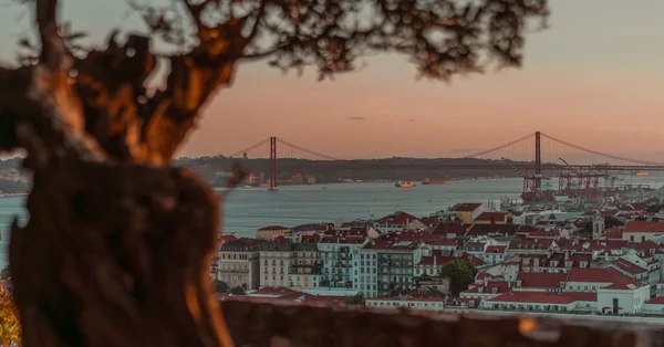 Dusk over Lisbon rooftops toward the 25 de Abril bridge and the Tagus river